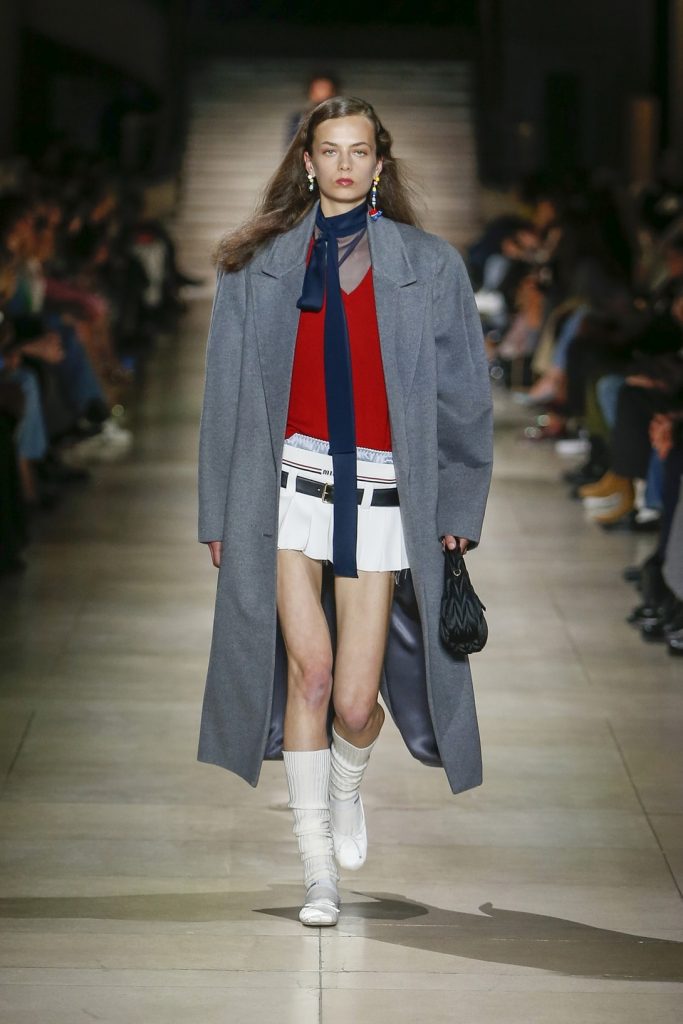 Modelo da Miu Miu usando sapatilhas brancas, desfilando no Paris Fashion Week. 